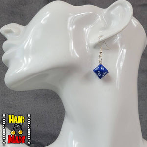 A pair of plastic blue 10-sided dice charms, hanging from a silver French hook, displayed on a white mannequin head.