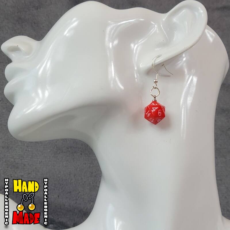 A plastic red D20 dice, hanging from a silver French hook, displayed on a white mannequin head.