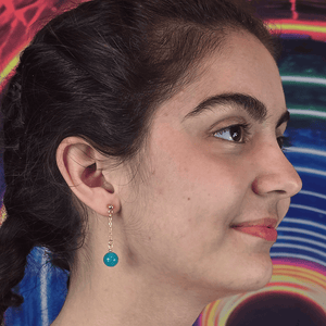 Model wearing Aquamarine Ascension Sphere Anime Earrings with aquamarine gemstone spheres and gold chain accents.