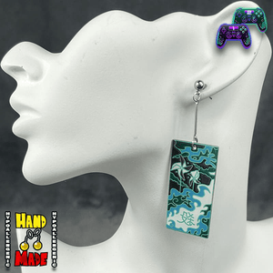 Large Acrylic Windmills Hanafuda Anime Earrings shown on a white molded stand, featuring a bold green and turquoise windmill motif with silver dropped posts.