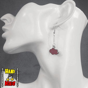 A pair of red cloud charms, dangling from a silver extender, attached to a silver French hook, displayed on a mannequin head.