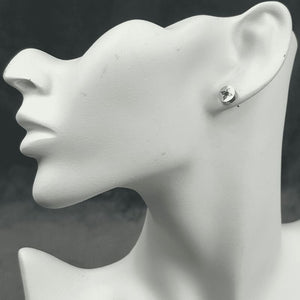 A pair of silver stud earrings featuring the Butterfly Crest design displayed on a mannequin head.