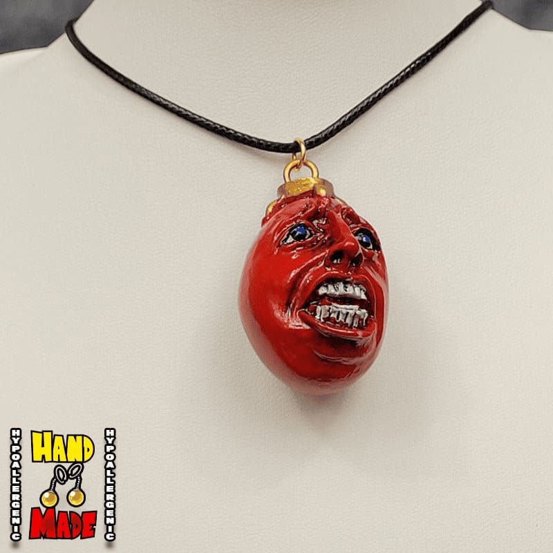 A crimson Behelit egg necklace from the anime Berserk, displayed on a mannequin neck.