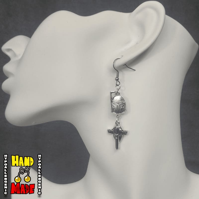 A pair of Boba Fett charm earrings displayed on a mannequin head, featuring silver color and intricate details of Boba Fett's iconic armor.