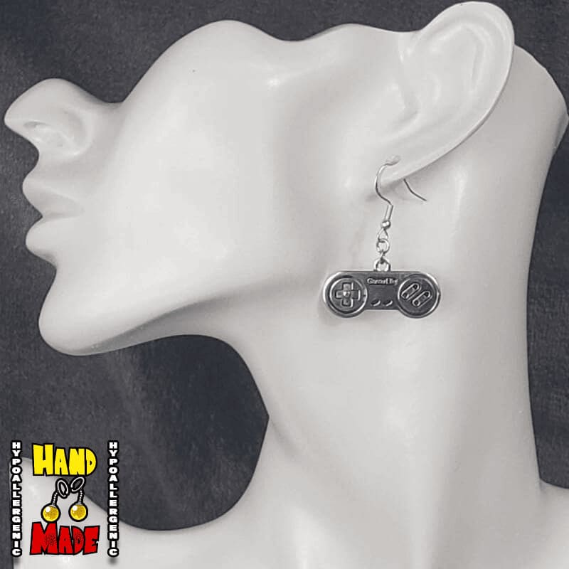 A pair of silver-colored controller earrings displayed on a mannequin head.