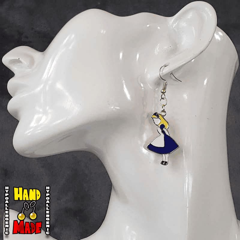 A pair of handmade gaming earrings, featuring an oversized enamel charm with a character in a blue dress, resembling Alice from 'Alice in Wonderland', displayed on a mannequin ear.
