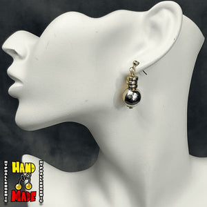A pair of gold-colored anime character-inspired earrings displayed on a mannequin head.