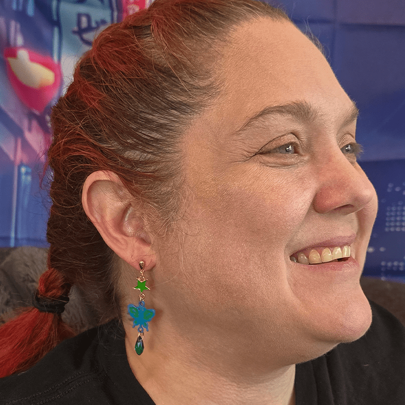 Model wearing Ladybug and Scarab Anime Earrings with butterfly and scarab charm accents and green bead details.