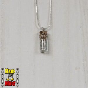 A glass jar, filled with Amazonite crushed crystal, hanging from a silver necklace.