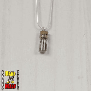 A glass jar, filled with Amethyst crushed crystal, hanging from a silver necklace.