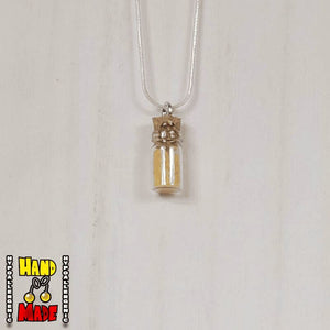 A glass jar, filled with Citrine crushed crystal, hanging from a silver necklace.