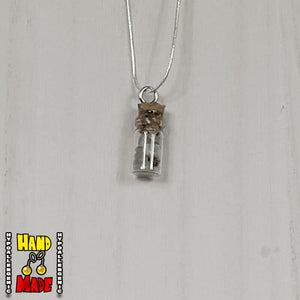 A glass jar, filled with Green Aventurine crushed crystal, hanging from a silver necklace.