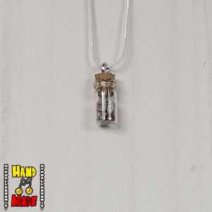 A glass jar, filled with Lapis Lazuli crushed crystal, hanging from a silver necklace.