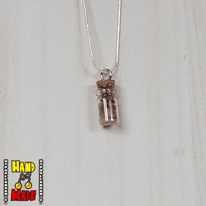 A glass jar, filled with Red Agate crushed crystal, hanging from a silver necklace.