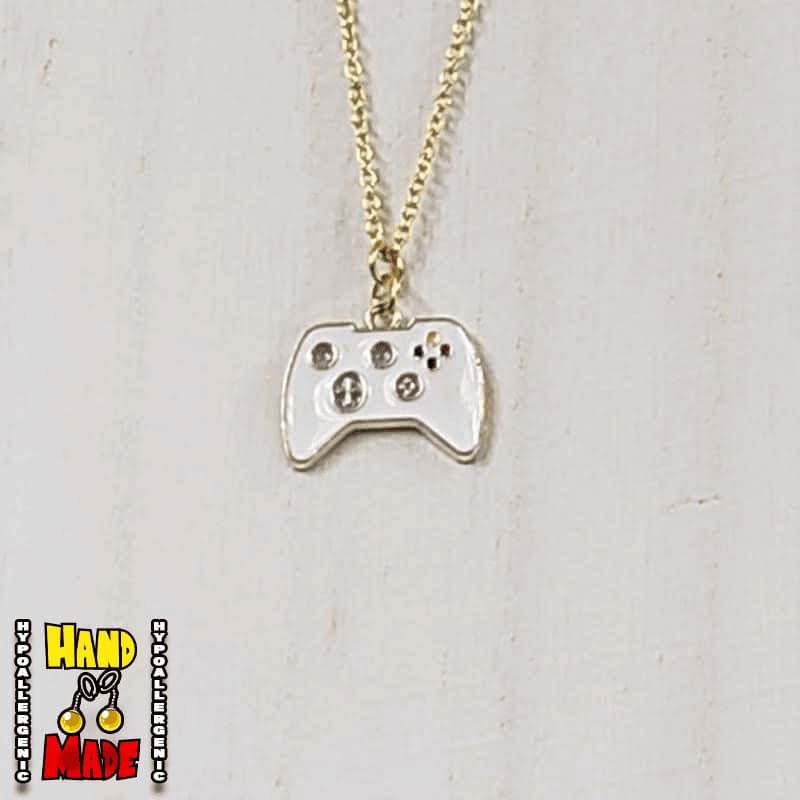 A pair of white gold painted video game controller-shaped earrings, hanging from a gold necklace, displayed on a white mannequin head.