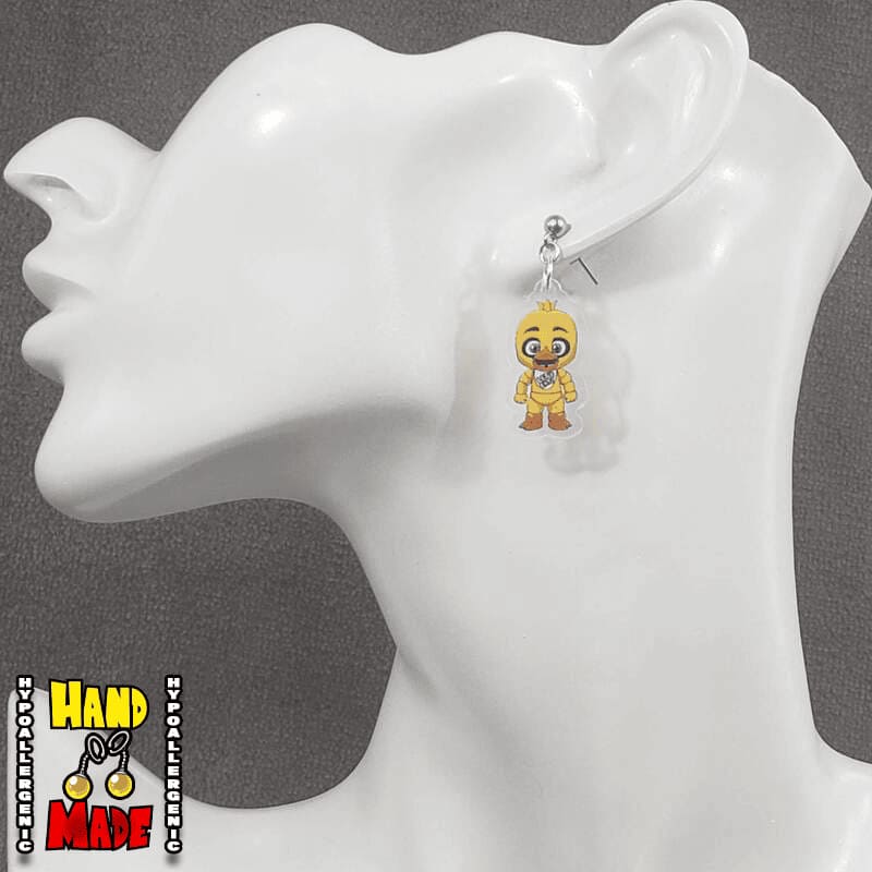 A pair of yellow acrylic earrings designed to resemble the character Chica from the 5 Nights at Freddy's game franchise, displayed on a mannequin head.