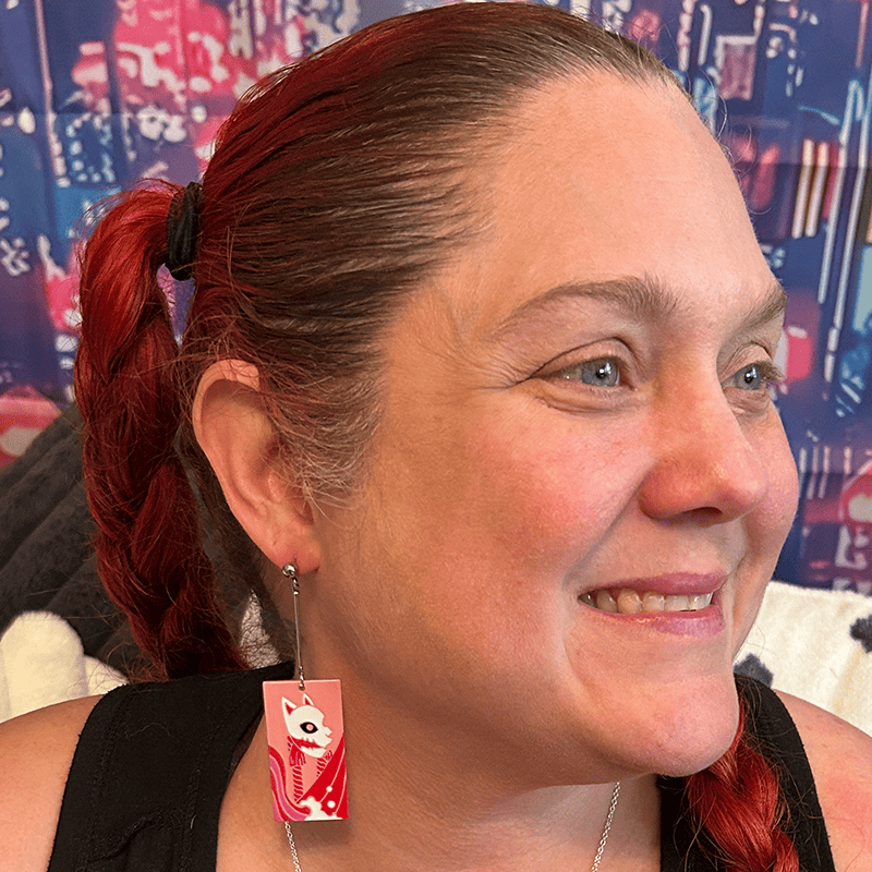Model wearing the large Acrylic Fox Mask Hanafuda Anime Earrings, showcasing the salmon-colored charm hanging lower on the ear from sterling silver dropped posts.