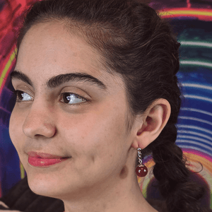 Model wearing Crimson Ascension Anime Earrings with red agate gemstone spheres and sterling silver dropped posts.