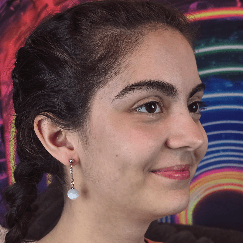 Model wearing Ivory Ascension Anime Earrings with white agate gemstone spheres and sterling silver dropped posts.