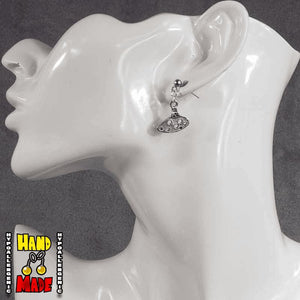 A pair of silver ocarina-shaped charms, hanging from a silver dropped post, displayed on a mannequin head.