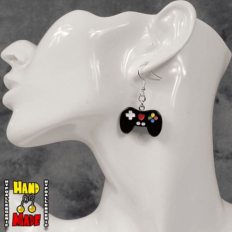 A pair of black plastic video game controller-shaped earrings displayed on a mannequin head.