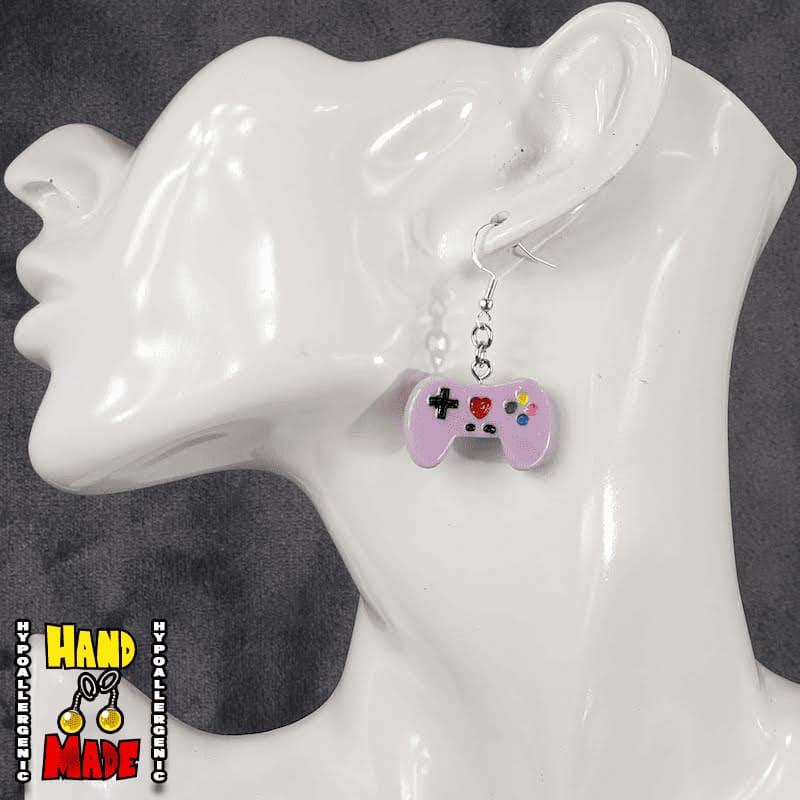 A pair of purple plastic video game controller-shaped earrings displayed on a mannequin head.