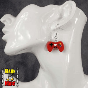 A pair of red plastic video game controller-shaped earrings displayed on a mannequin head.