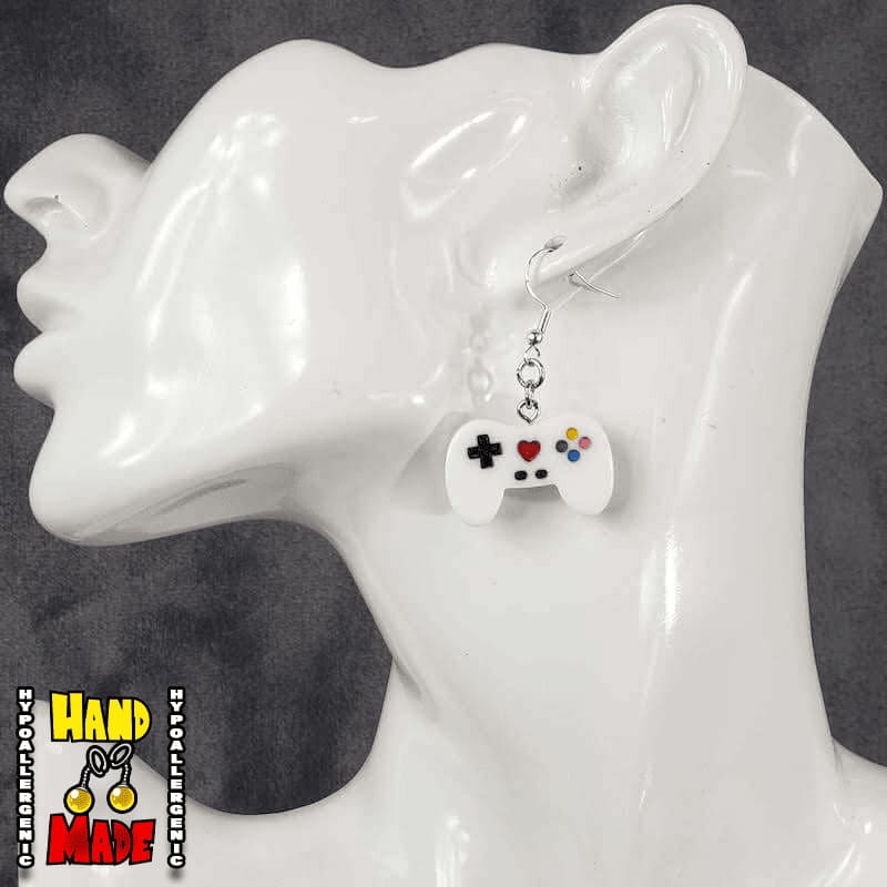 A pair of white plastic video game controller-shaped earrings displayed on a mannequin head.