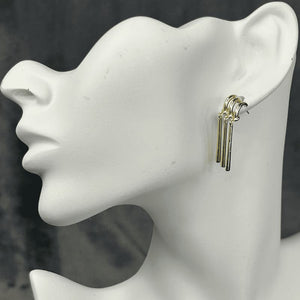 Three golden bars hang from three gold hooks that are consolidated into one post.