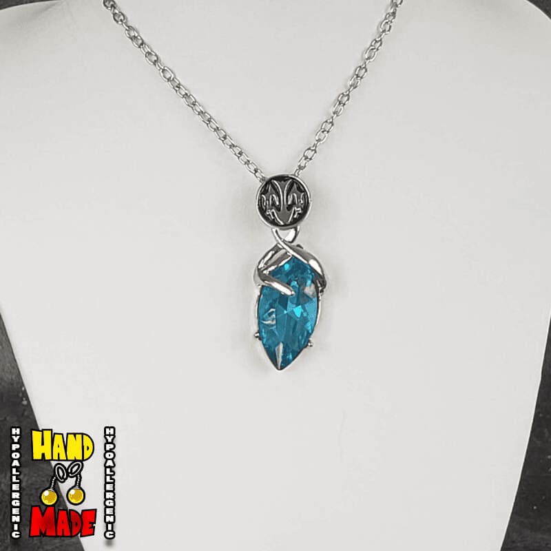 A sapphire-blue pendant, with silver details, suspended from a silver chain, displayed on a mannequin.