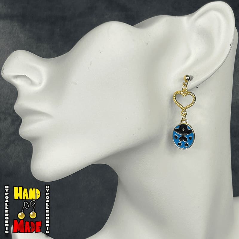 A pair of blue ladybug earrings with gold heart and post, displayed on a mannequin ear.
