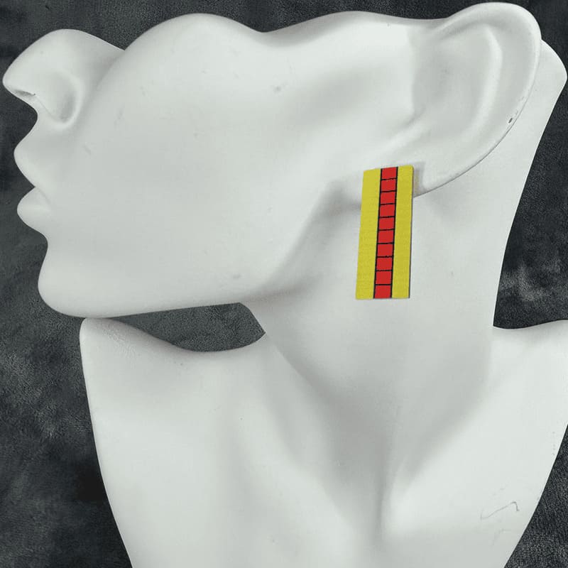 A pair of Tetta Kisaki stud earrings featuring a yellow and red design on a mannequin ear.