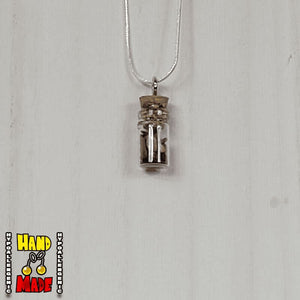 A glass jar, filled with Tigers Eye crushed crystal, hanging from a silver necklace.