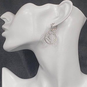 A pair of cutout BB-8 earrings displayed on a mannequin head.
